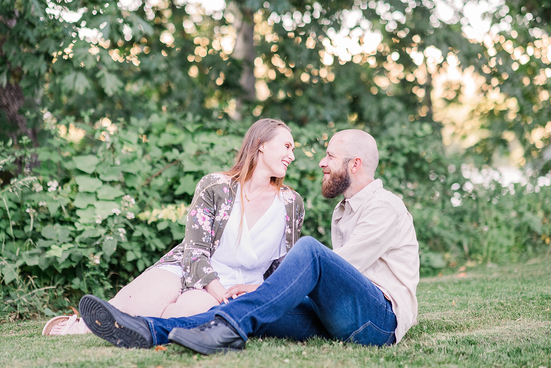 couple sits in the grass during Engagement session at Owen Rose Garden