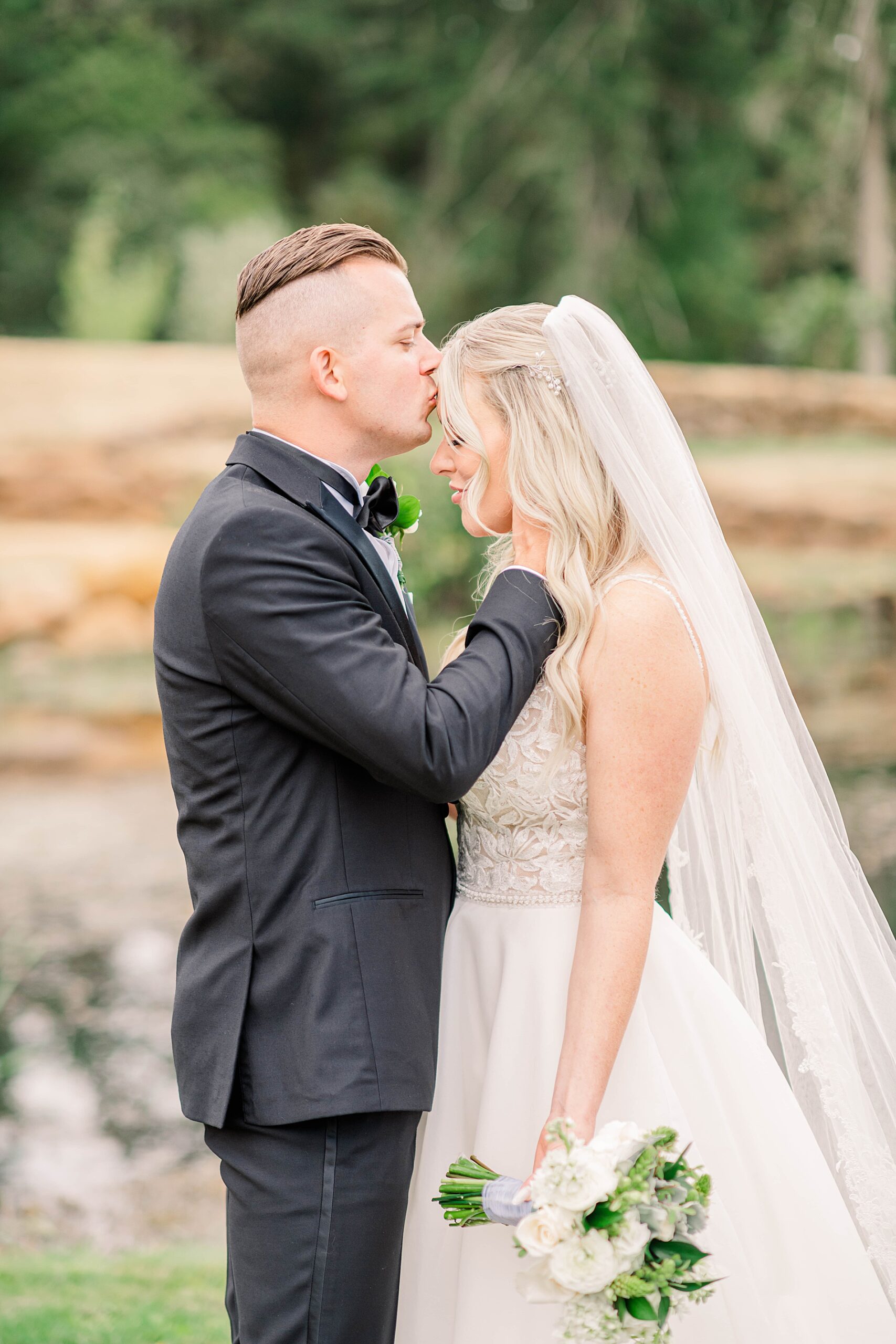 groom kisses bride's head during first look