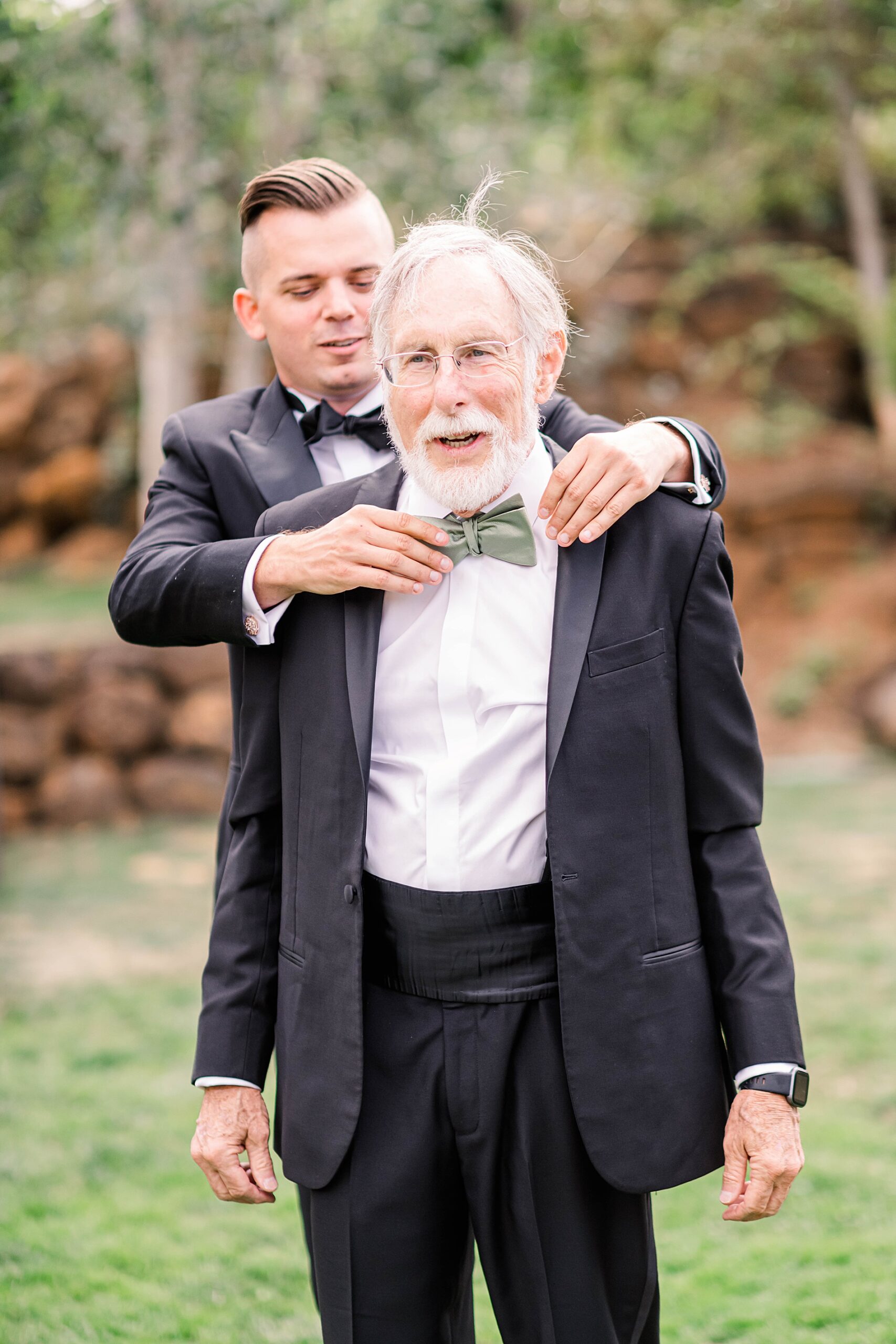 groom helps father of the bride with bowtie