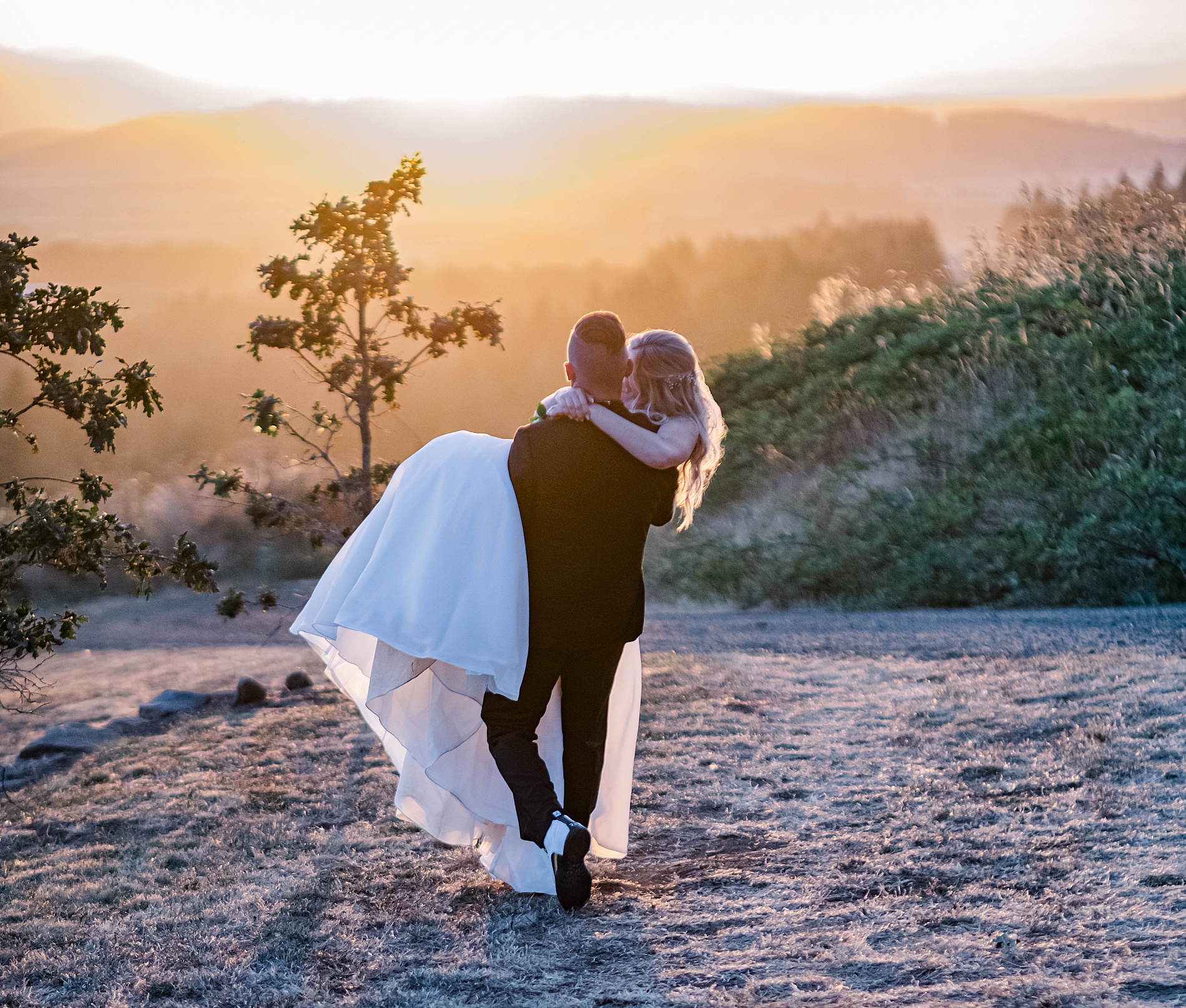 intimate wedding portraits of groom holding bride as they watch the sunset