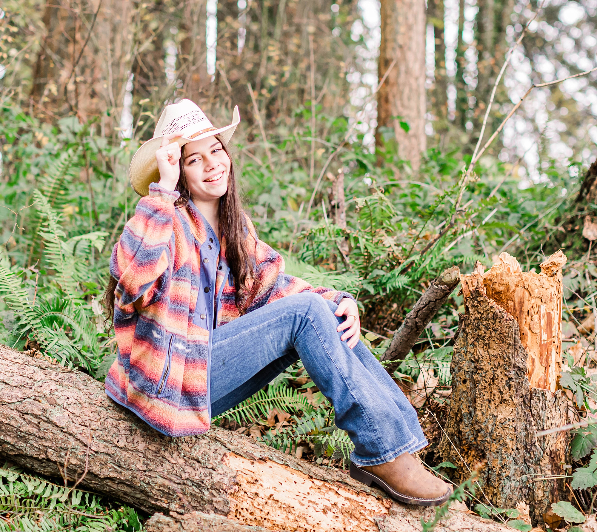 senior girl sits on tree trunk in forest in Albany Oregon