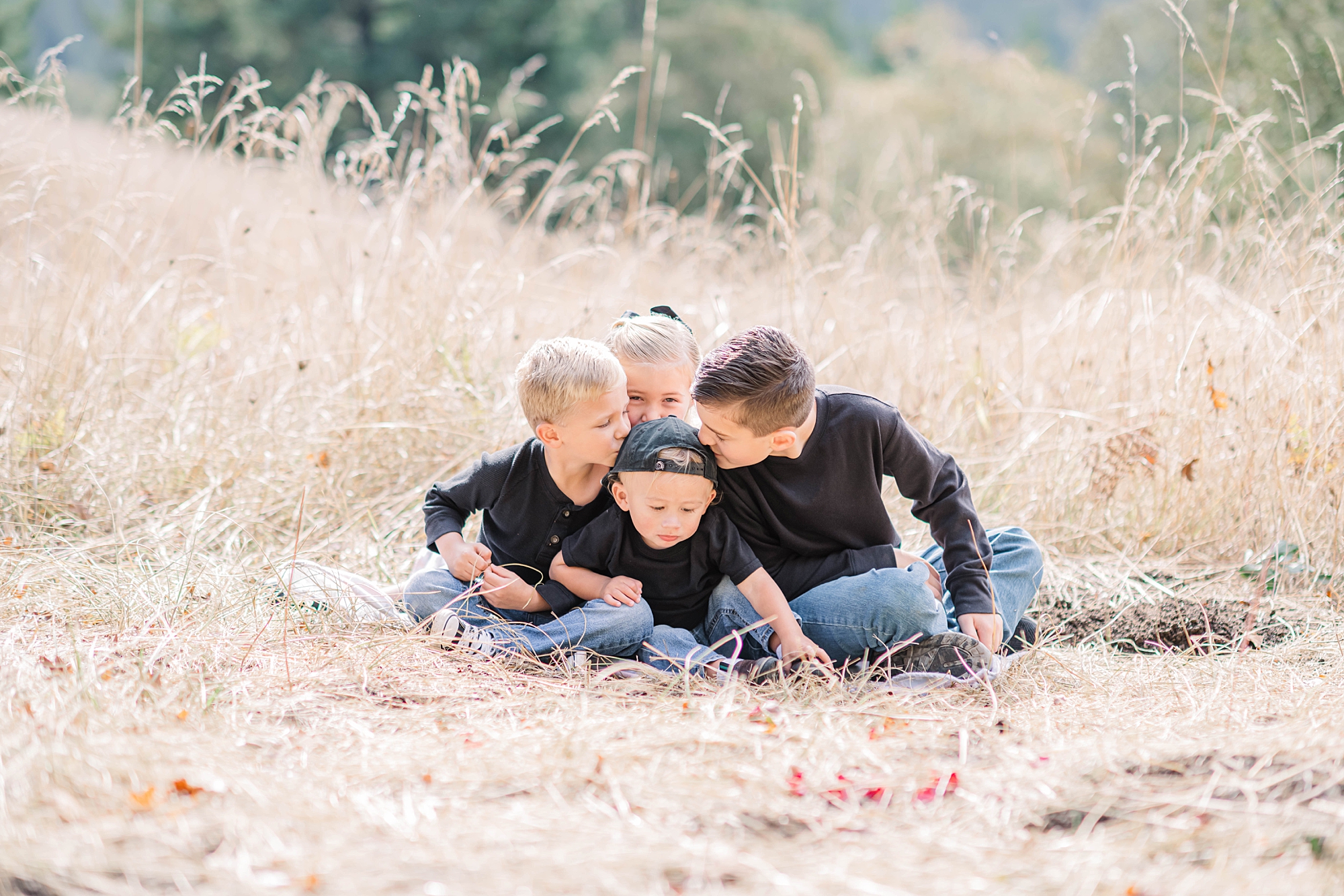 four siblings sit together in the tall grass