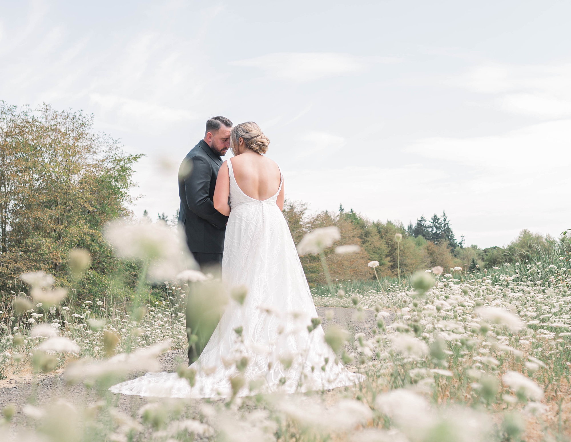 bride and groom walk through field of flowers